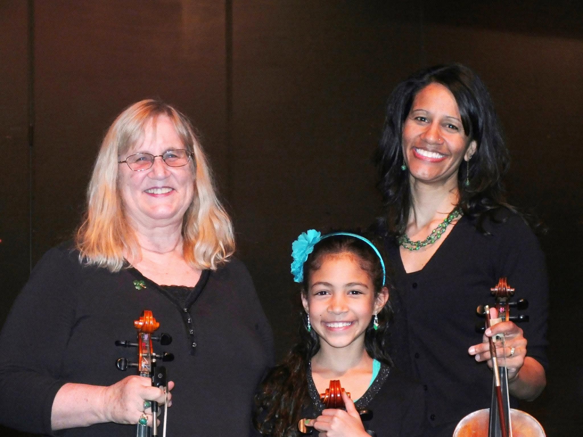 Dr. Colleen Snyder with her daughter and grandaughter, all three holding their instruments after a performance.